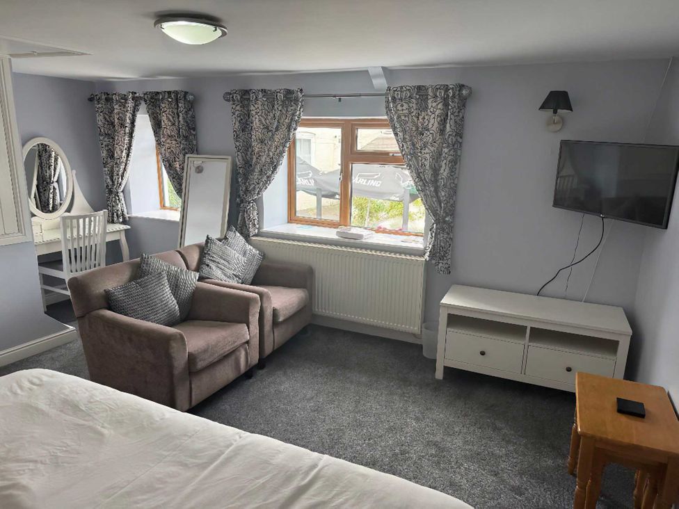 A bedroom with a sofa and a desk at Triangle Inn Coachouse Rhayader