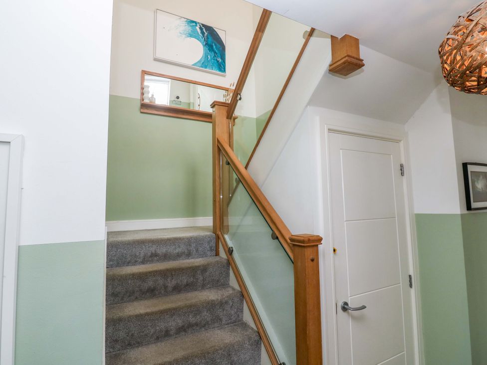 A staircase with a wooden railing and walls in a hallway at 6 Chapel Rock Close Perranporth
