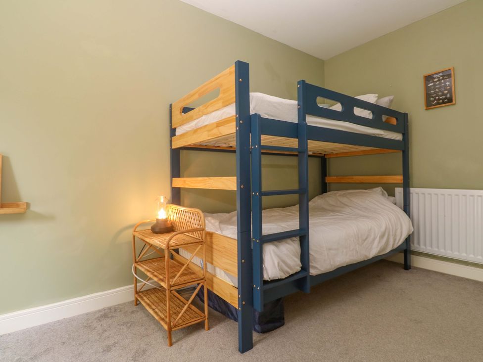 A bedroom with a bunk bed and a nightstand with a lamp at 6 Chapel Rock Close Perranporth
