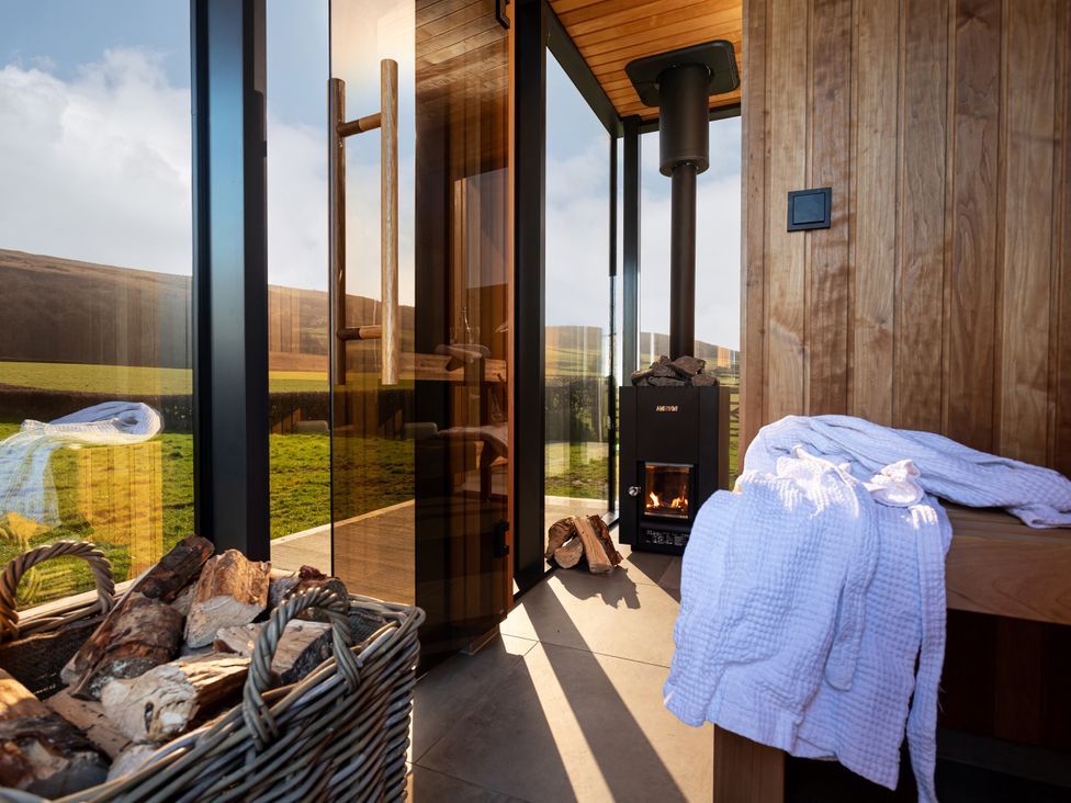 A sauna with wood basket and fireplace at Middle Longlands in Cartmel