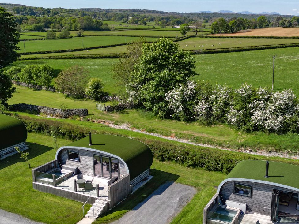 Two cabins with grass roofs and a deck at High Longlands in Cartmel