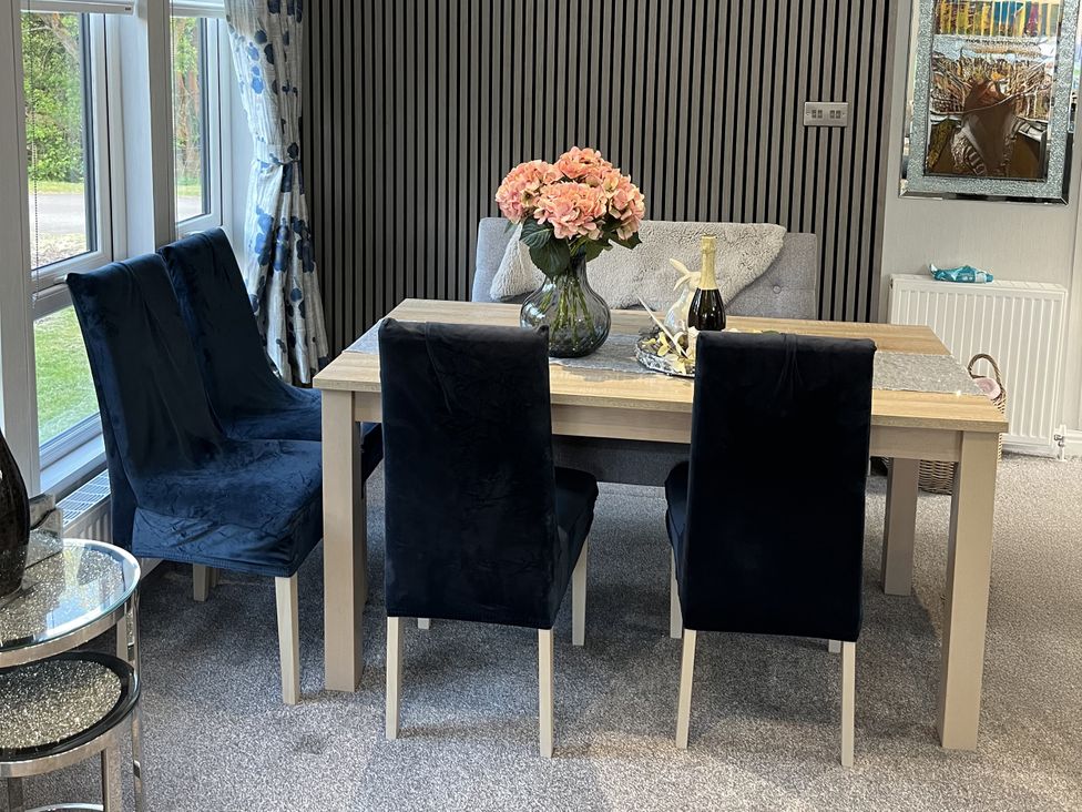 A dining room with a table and chairs at Loluke Lodge on The Lake, 5 Coniston Drive, Borwick near Carnforth