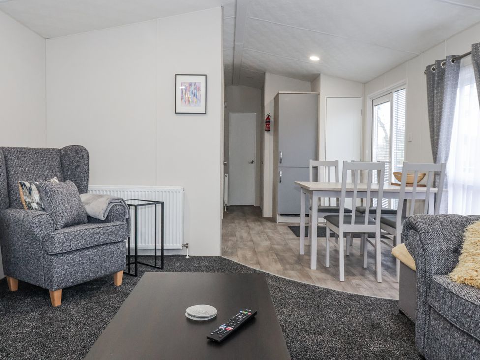 A living room with an armchair and a dining table at Lazy Daze Carnaby near Bridlington