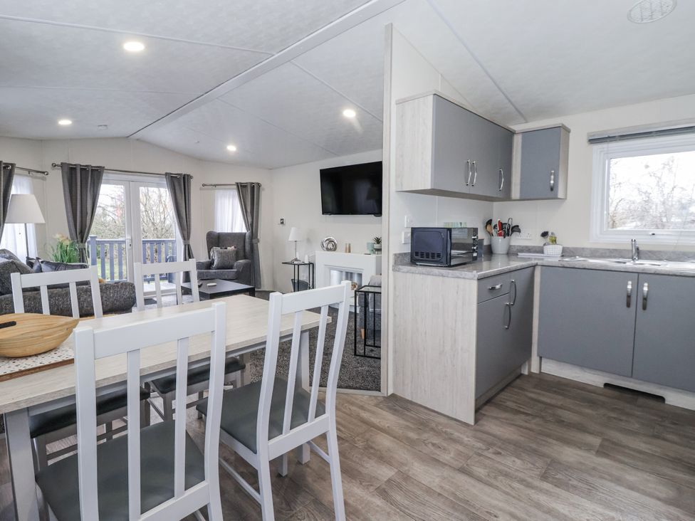 A living room and kitchen area with a table and chairs at Lazy Daze in Carnaby near Bridlington