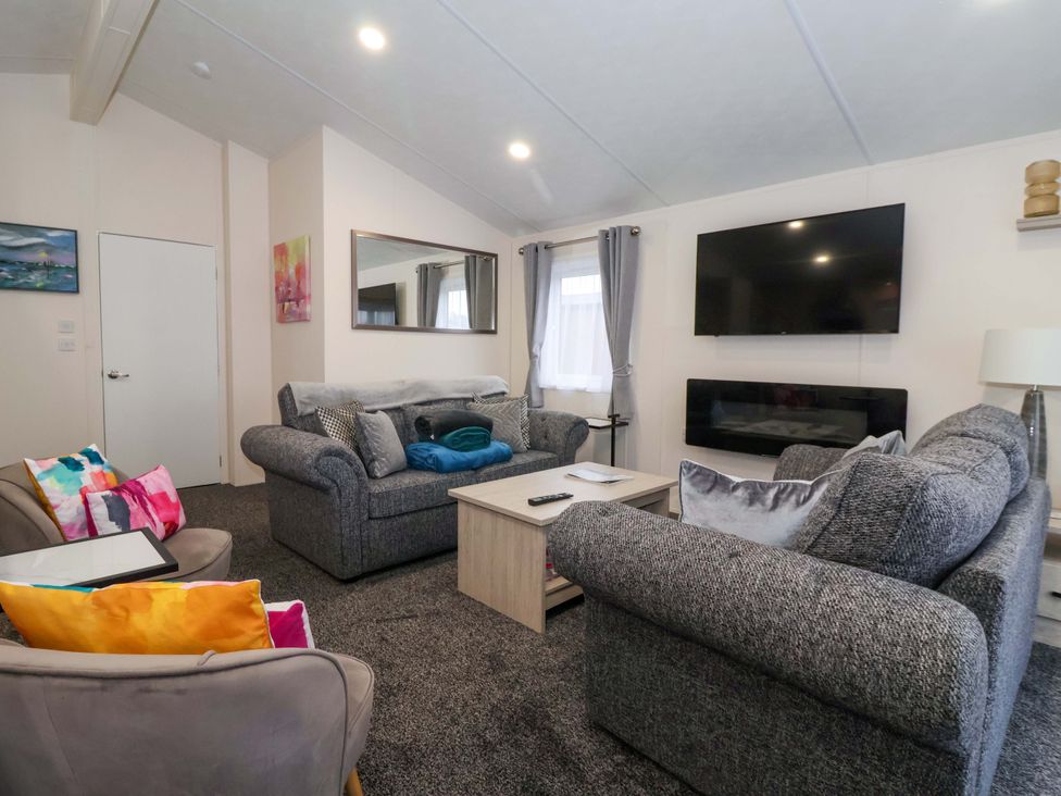 A living room with a sofa and television at Brighter Daze in Carnaby near Bridlington