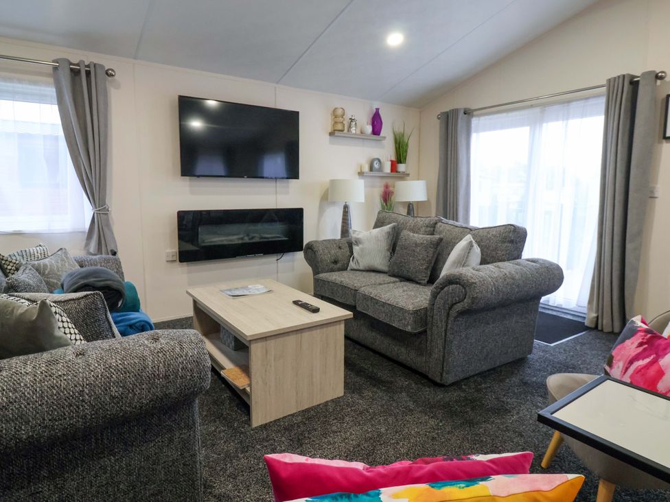 A living room with a sofa and television at Brighter Daze in Carnaby near Bridlington