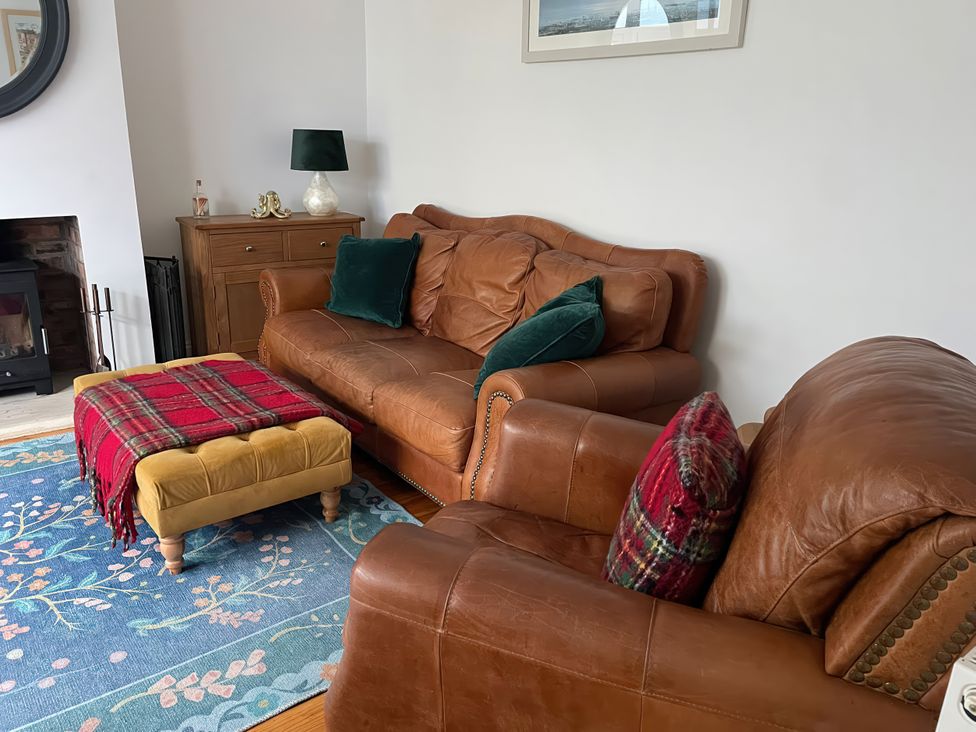 A living room with leather furniture and a rug at The Nook in Weymouth