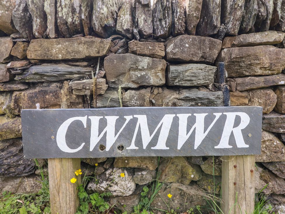 A slate sign with the text CWMWR in front of a stone wall at Cwmwr Penybontfawr