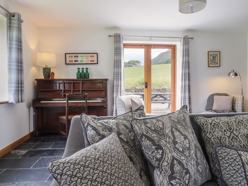 A living room with a piano and sofa at Cwmwr in Penybontfawr
