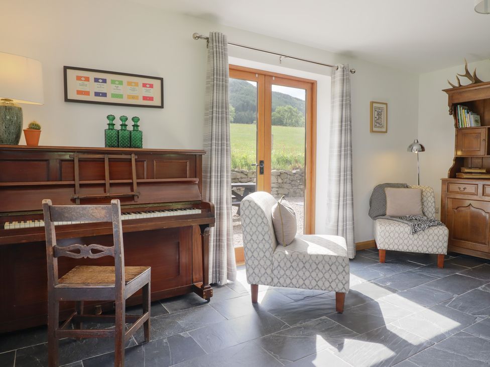 A living room with a piano and seating at Cwmwr in Penybontfawr