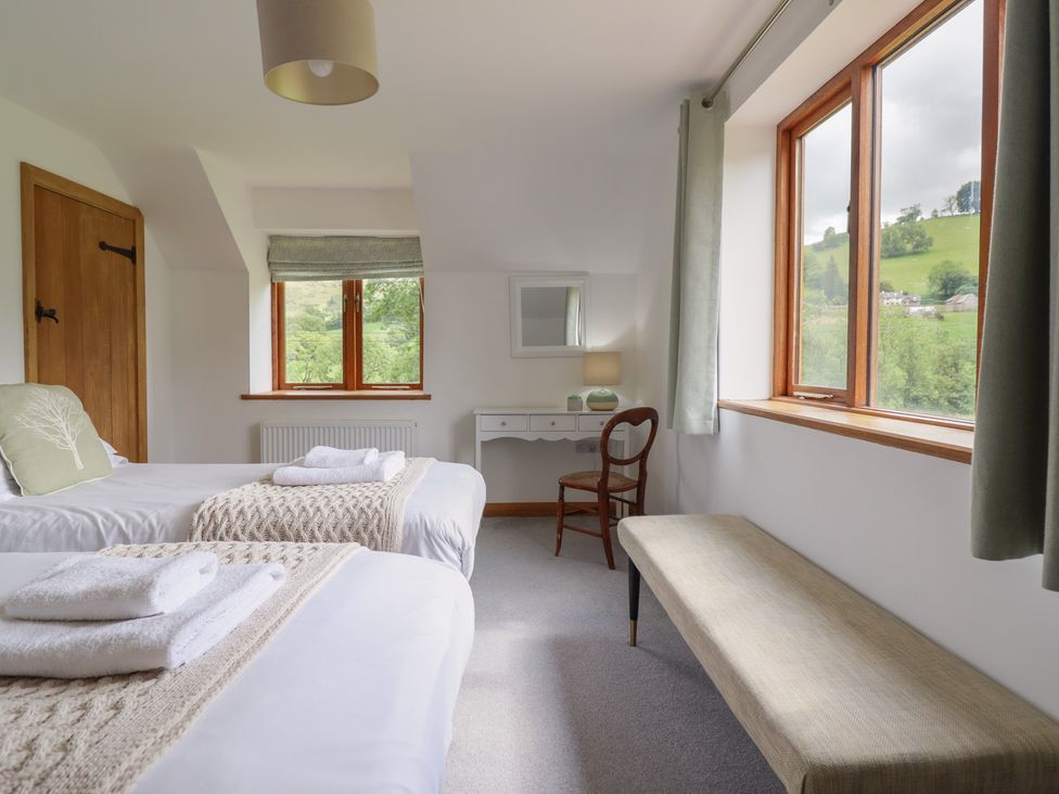 A bedroom with two beds and a table at Cwmwr in Penybontfawr