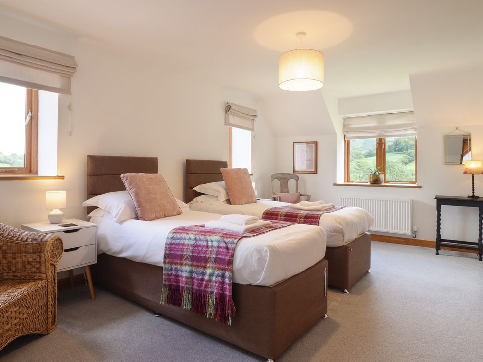A bedroom with two beds and a nightstand at Cwmwr in Penybontfawr