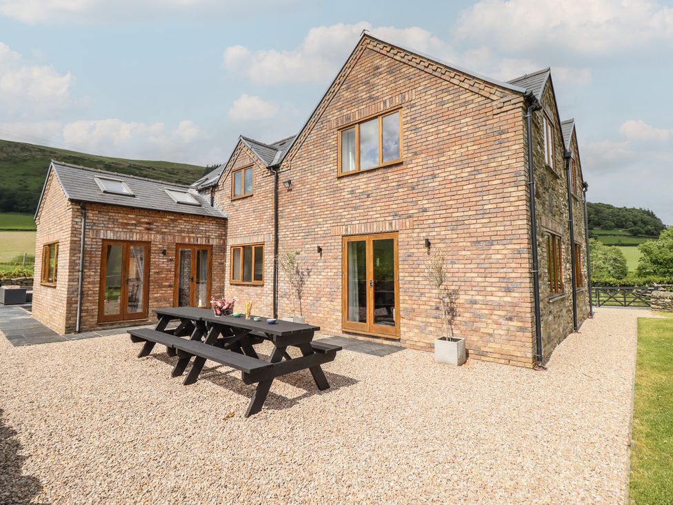 An outdoor area with a brick house and table at Cwmwr Penybontfawr