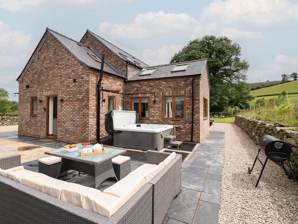 An outdoor area with seating and a hot tub at Cwmwr in Penybontfawr