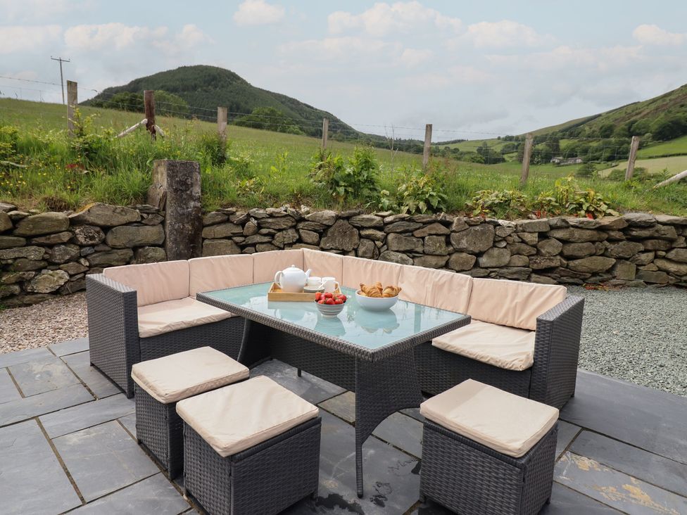 An outdoor seating area with a table and food items at Cwmwr in Penybontfawr