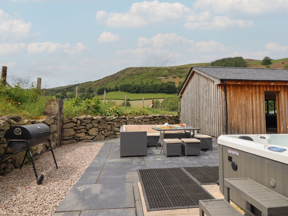 An outdoor area with a grill and hot tub at Cwmwr Penybontfawr
