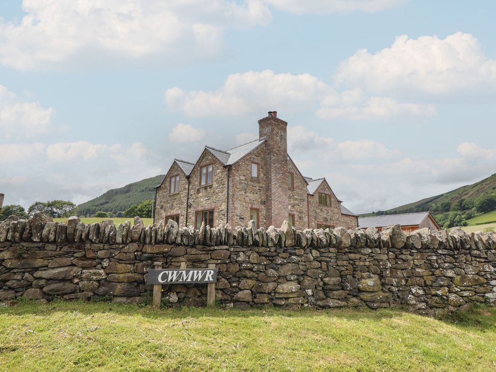 A house and stone wall with a sign at Cwmwr in Penybontfawr