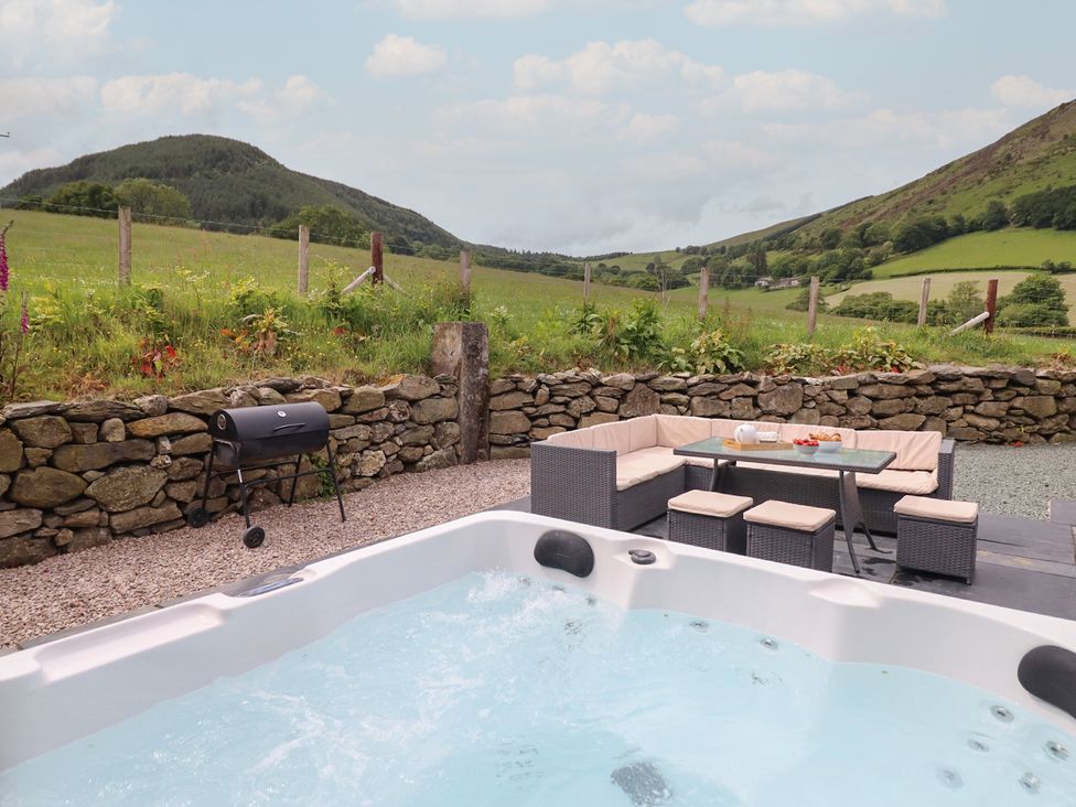 An outdoor area with a hot tub and seating at Cwmwr Penybontfawr