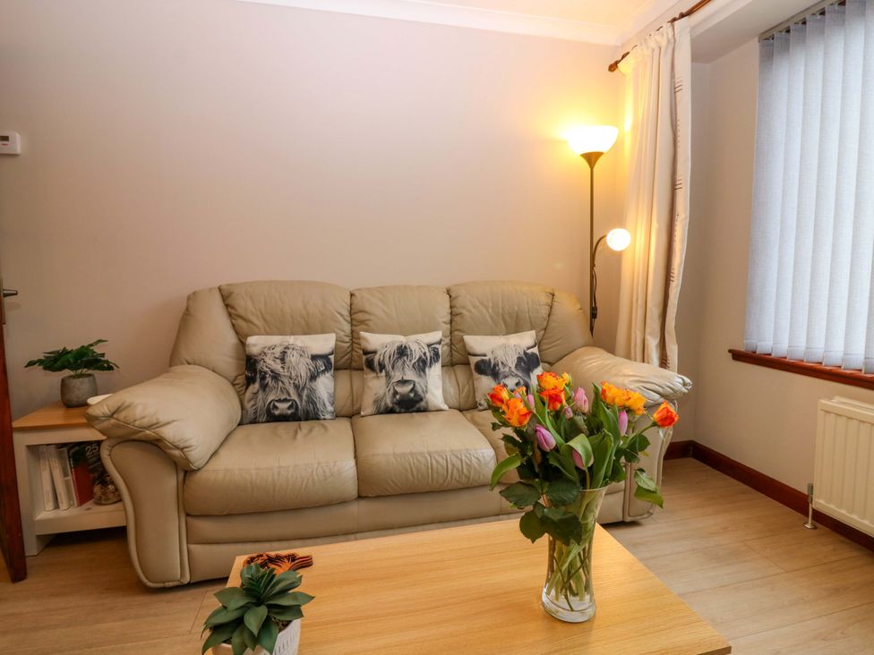 A living room with a sofa and flower vase at 48 Edenbank Road in Cupar, Fife