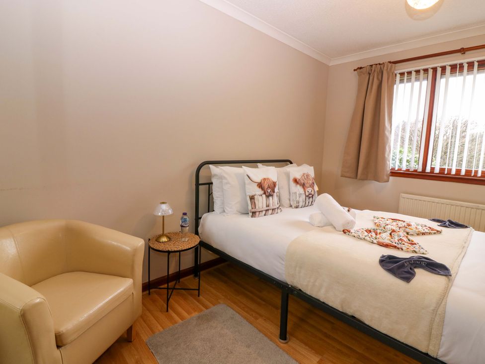 A bedroom with a bed and armchair at 48 Edenbank Road, Cupar, Fife