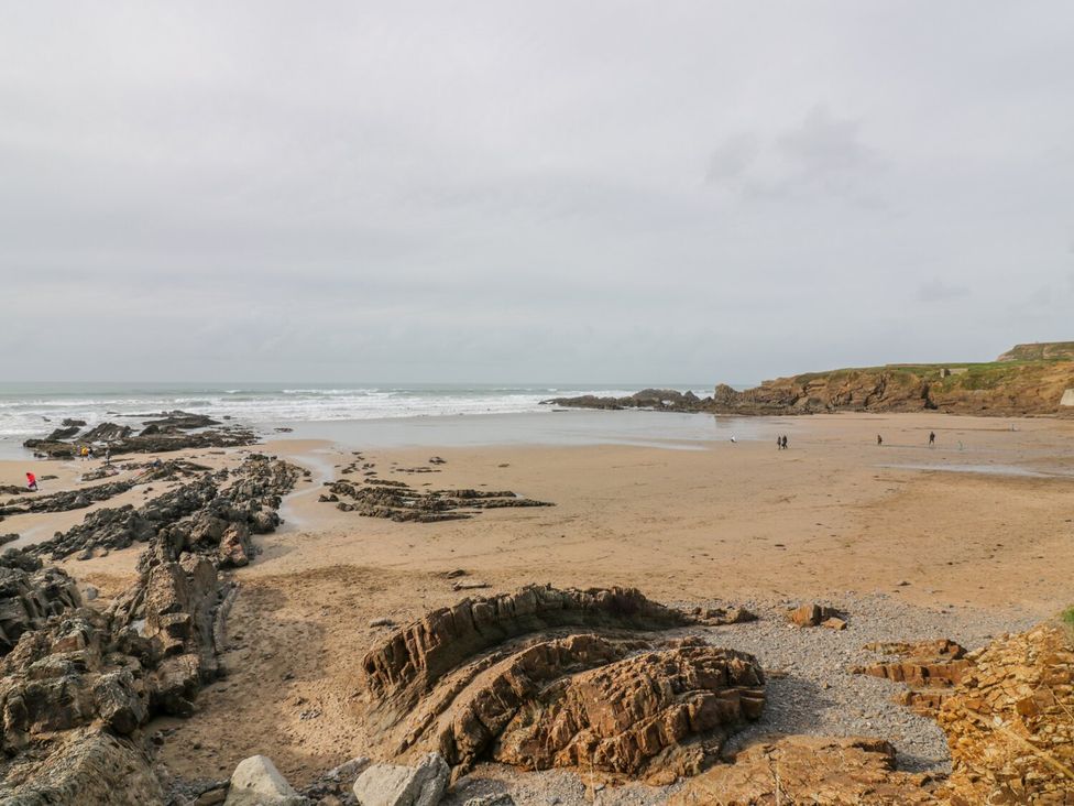 A beach with exposed rock formations and people walking near the shore at Munro Lodge in Woolsery near Woolfardisworthy