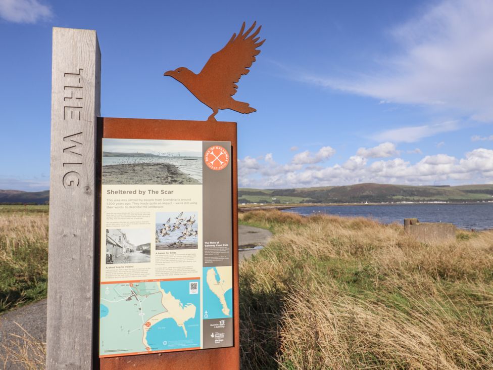 A sign with a bird sculpture at a coastal view at Kringlands Kirkcolm