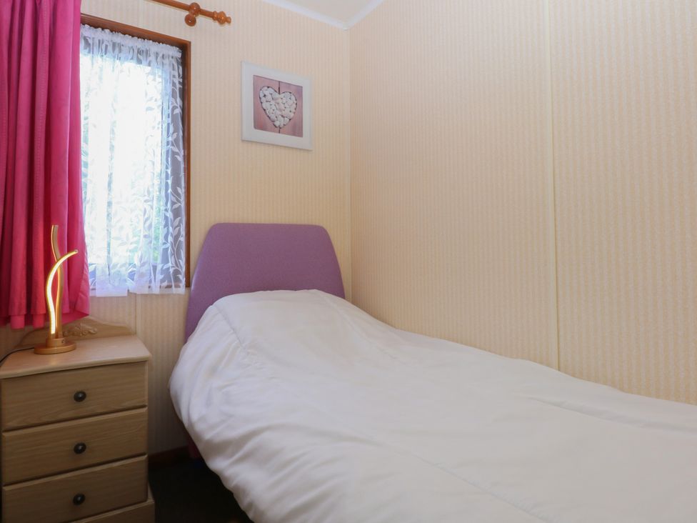 A bedroom with a bed and a window at 16 Forest Lodge in Chwilog