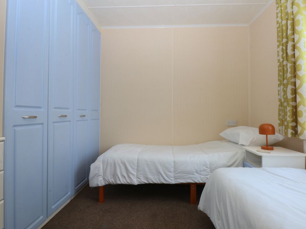 A bedroom with two beds and a wardrobe at 16 Forest Lodge in Chwilog