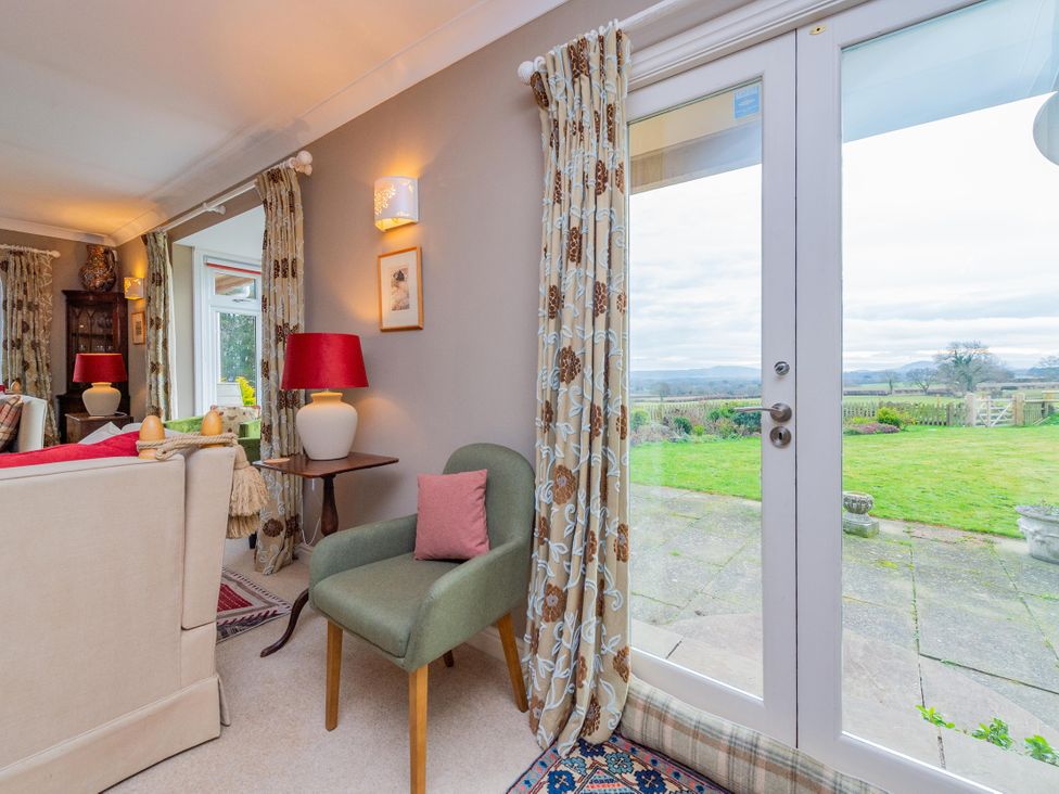 A living room with a chair and door leading outside at Pear Tree Cottage in Church Pulverbatch near Dorrington