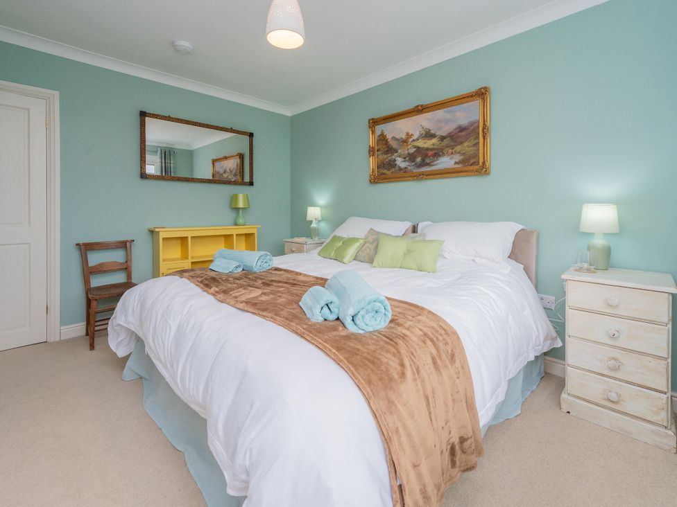 A bedroom with a bed, side tables, and a mirror at Pear Tree Cottage in Church Pulverbatch near Dorrington