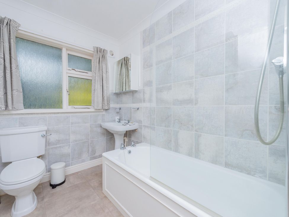 A bathroom with a toilet, bathtub, sink, and mirror at Pear Tree Cottage in Church Pulverbatch near Dorrington