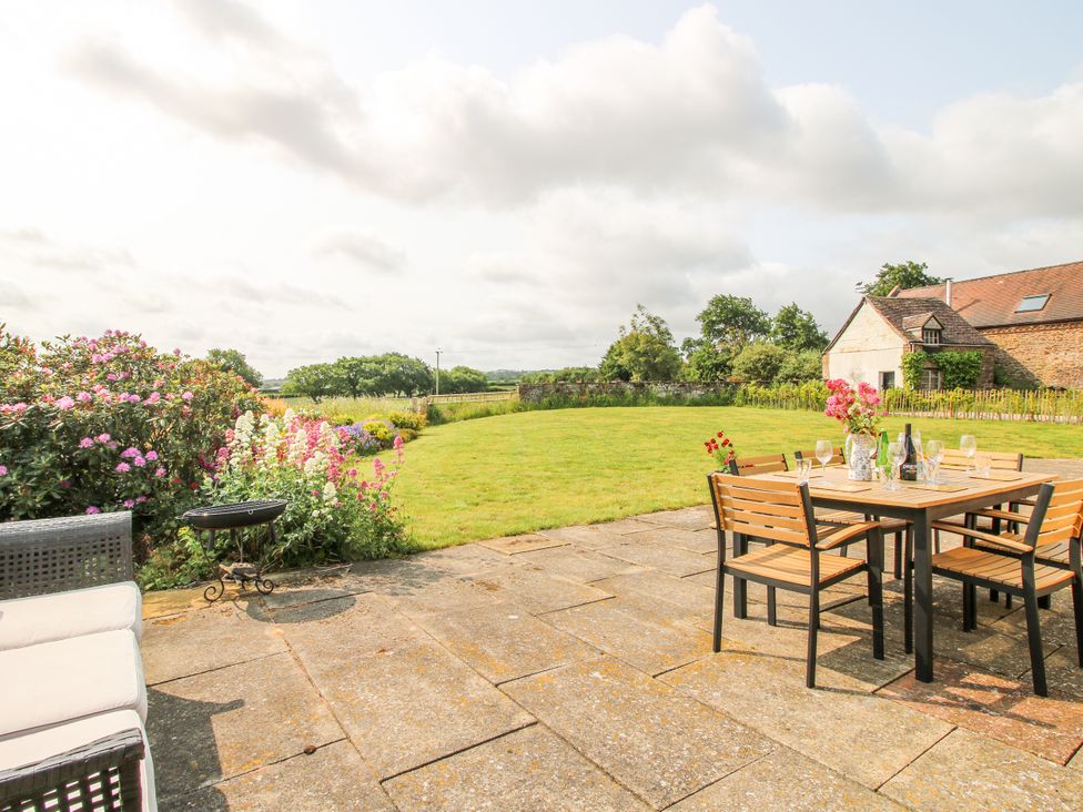 A patio with a table and chairs, surrounded by flowers at Pear Tree Cottage in Church Pulverbatch near Dorrington
