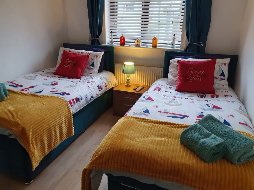 A bedroom with two single beds and a nightstand at Normandy in Nefyn