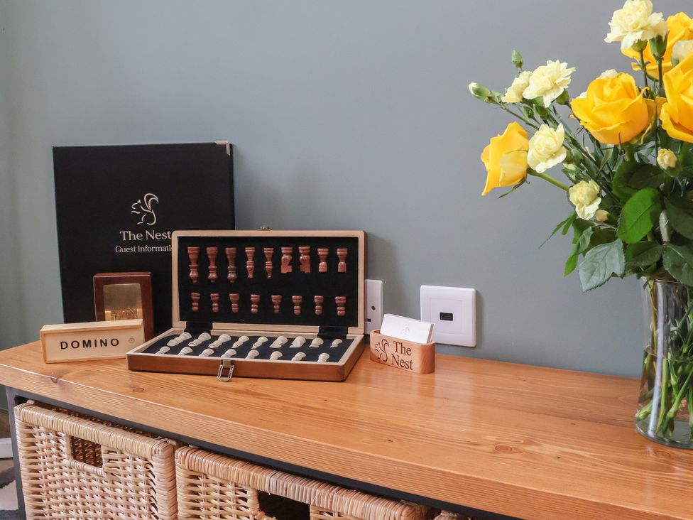 A living room with a flower vase and a guest information booklet at The Nest in Prestatyn