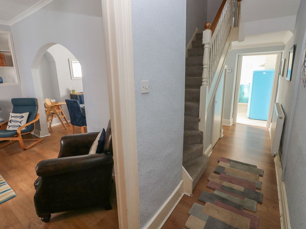 A hallway with a staircase and armchairs at Longmoor in Tenby