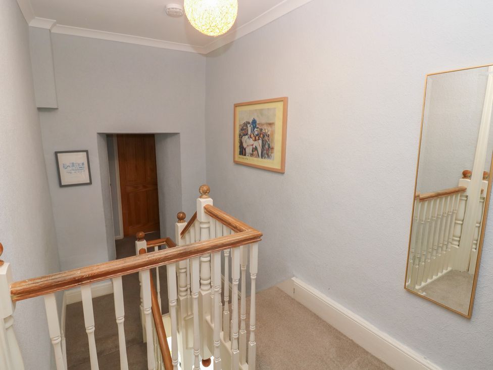 A hallway with a staircase and a painting at Longmoor in Tenby