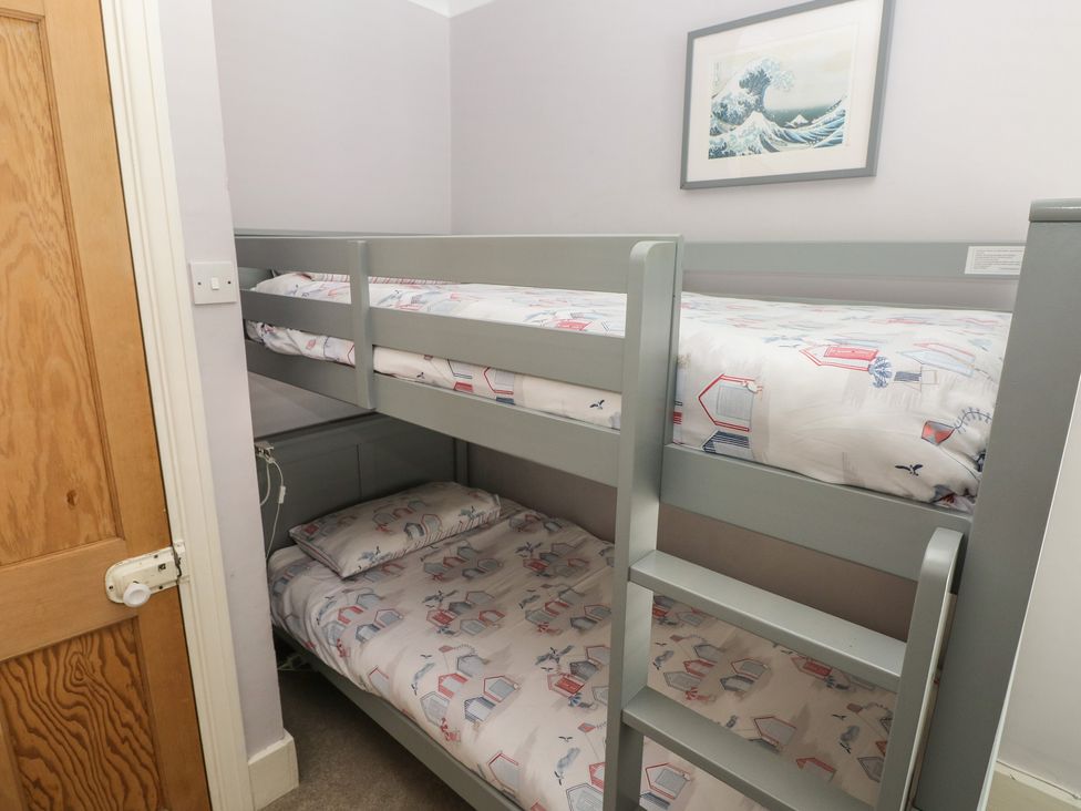 A bedroom with a bunk bed and artwork at Longmoor in Tenby