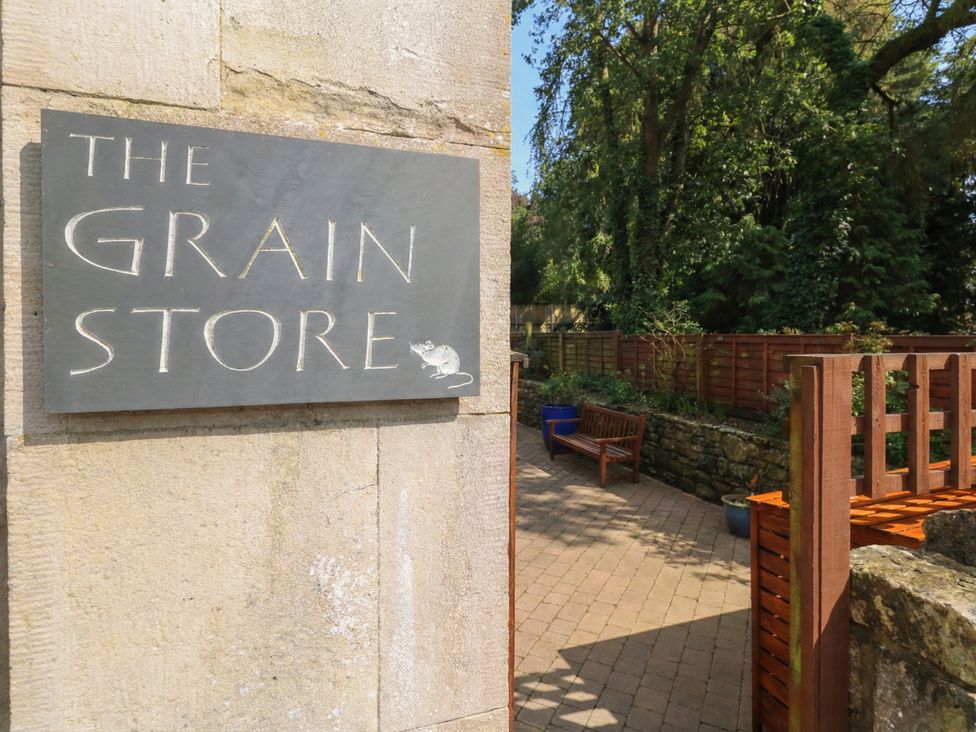 A sign for The Grain Store next to a path and plants at The Grain Store in Weymouth