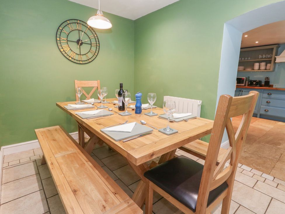A dining room with a wooden table and clock at The Grain Store in Weymouth