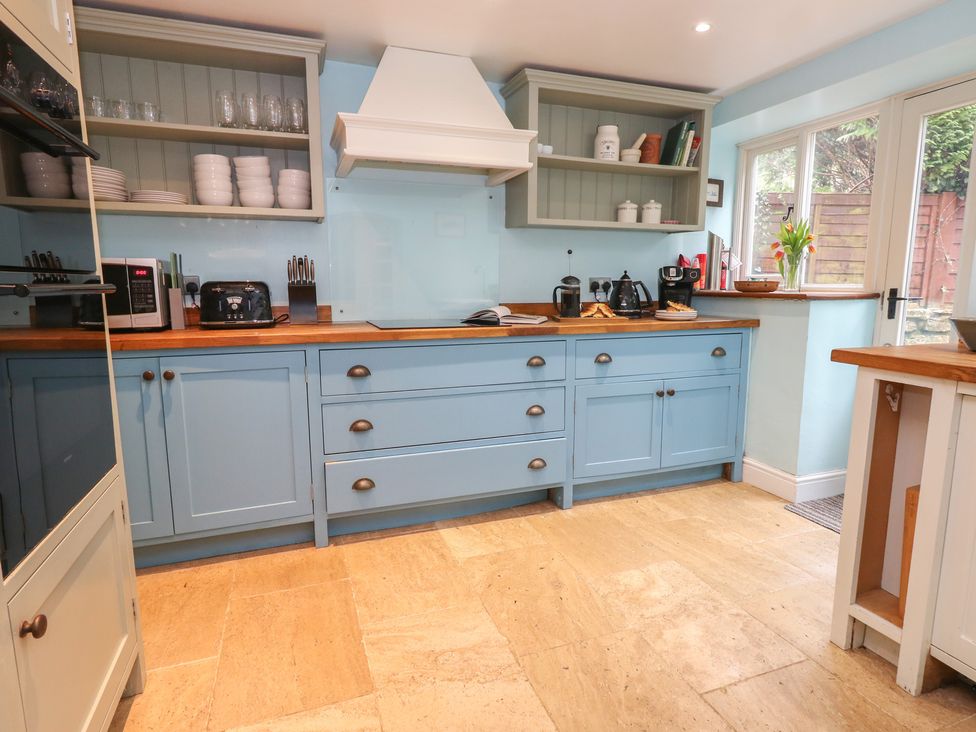 A kitchen with blue cabinets and wooden countertop at The Grain Store in Weymouth