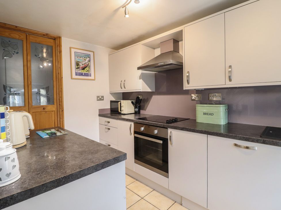 A kitchen with cabinets, oven, and a kettle at Bridgeway House in Blaenau Ffestiniog