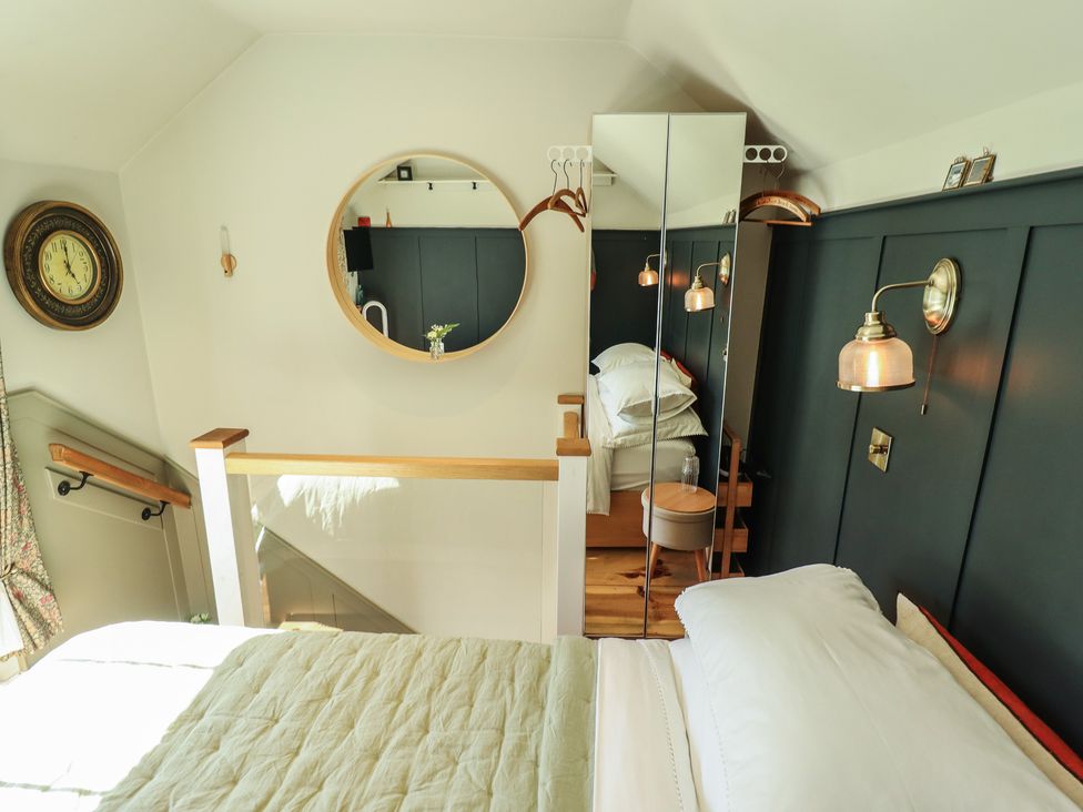 A bedroom with a bed and mirror at Hangmans cottage Horncastle
