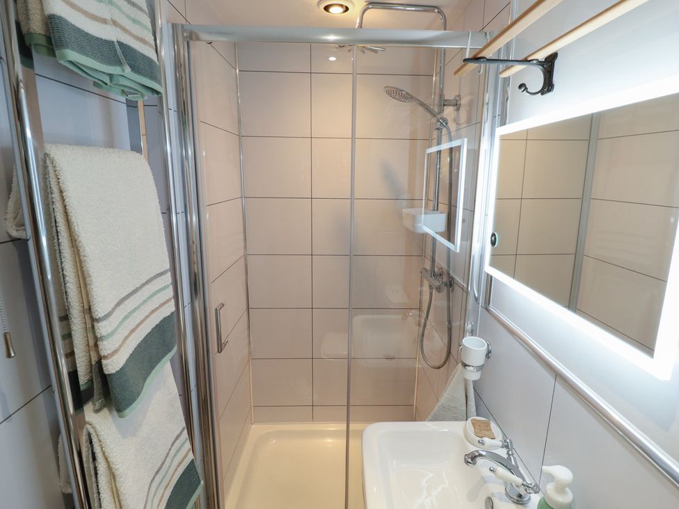 A bathroom with a shower, sink and towels at Hangmans cottage in Horncastle