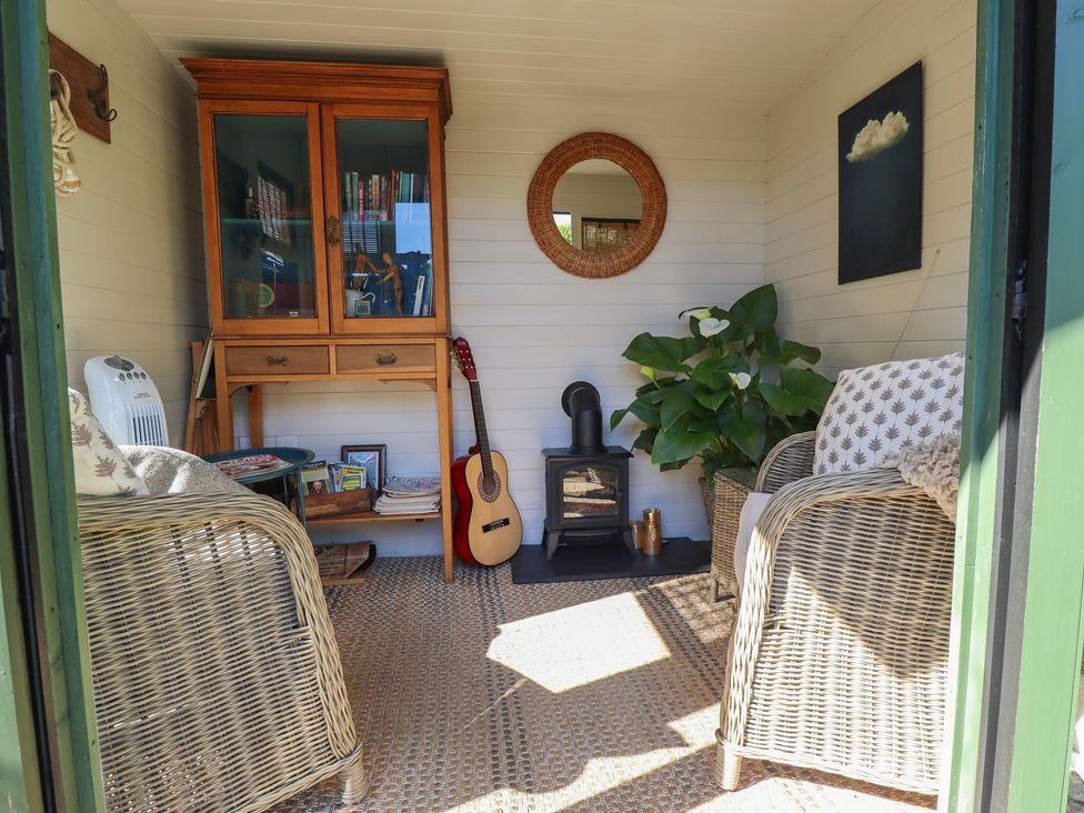 A snug with wicker chairs and a wooden cabinet at Hangmans cottage Horncastle