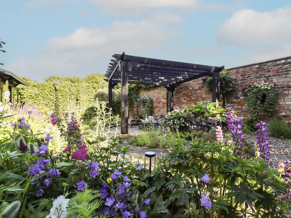 A garden with flowers and a pergola at Hangmans cottage in Horncastle