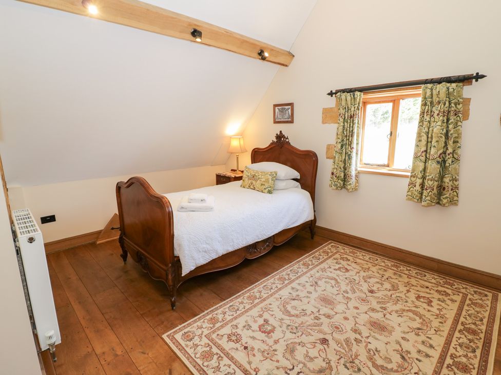 A bedroom with a wooden bed and window at Rookery Hall in Middle Hill near Broadway