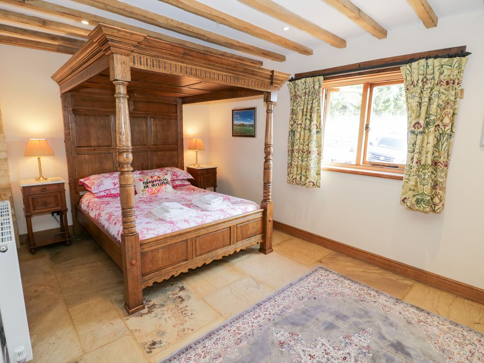 A bedroom with a four-poster bed and bedside table at Rookery Hall near Broadway