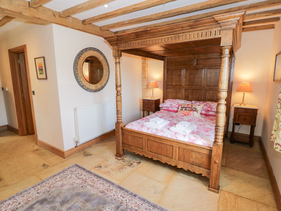 A bedroom with a four poster bed and bedside tables at Rookery Hall in Middle Hill near Broadway