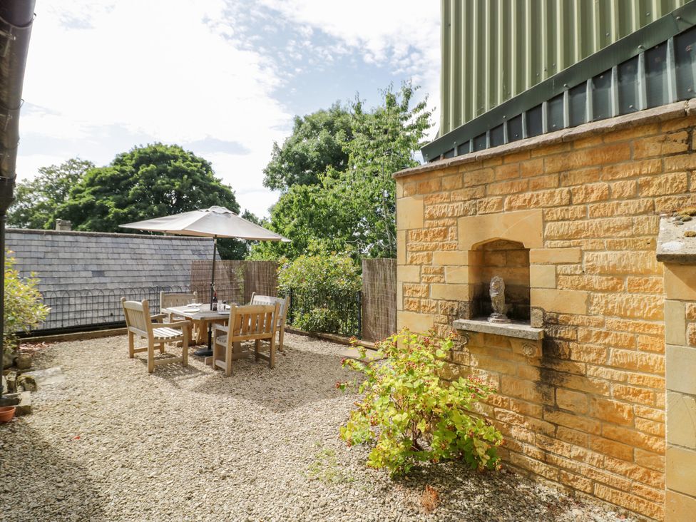 A patio with a table and chairs under an umbrella at Rookery Hall near Middle Hill