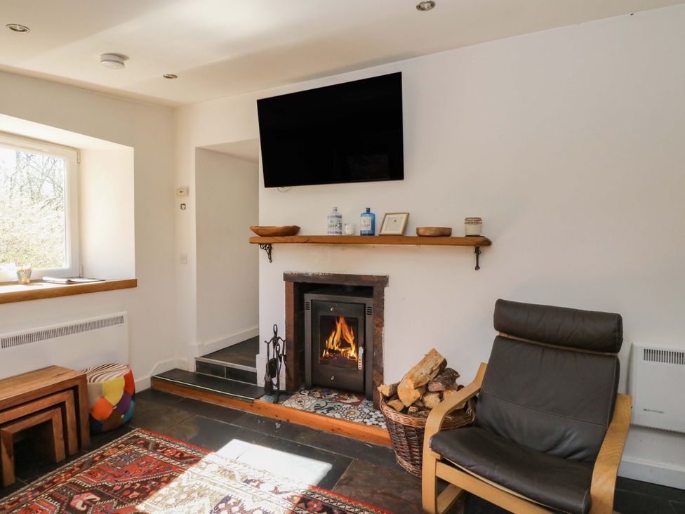 A living room with a fireplace and television at Gun Powder Cottage Tighnabruaich